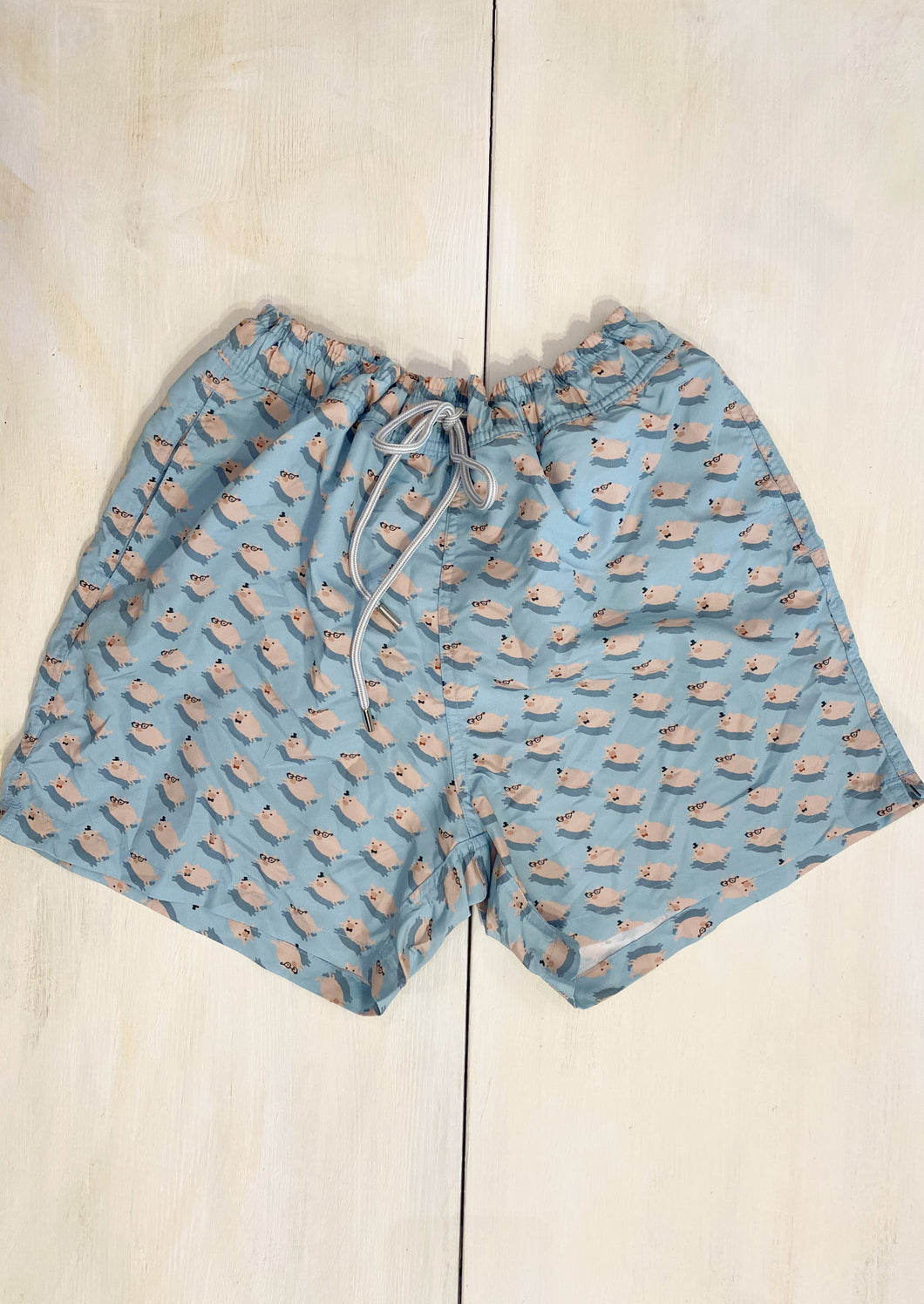 Boxer uomo colore azzurro chiaro con piccoli maialini rosa. Elastico in vita e coulisse per regolare la larghezza. Tasca con bottone dietro .   
